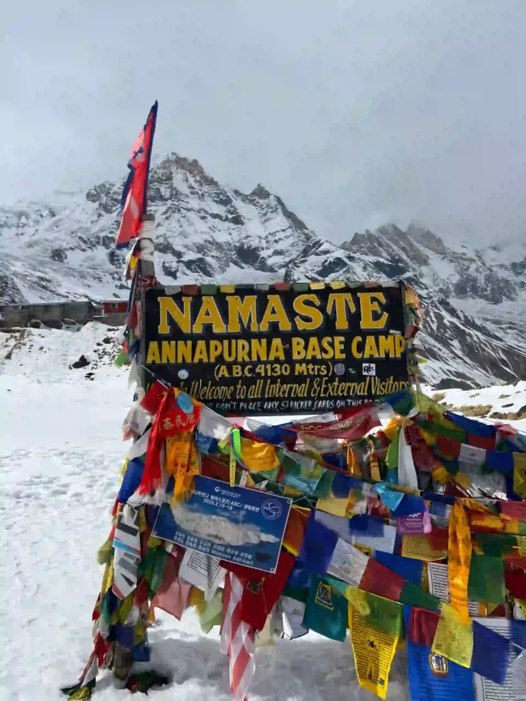 How much does trekking cost in nepal? (a realistic 2026 budget). 2 A view of the colorful prayer flags and snow-capped peaks at Annapurna Base Camp in Nepal.